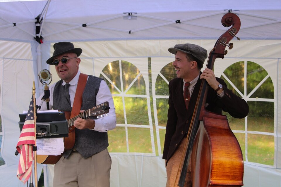 Deux musiciens en tenue vintage sous une tente de réception lors de l'événement