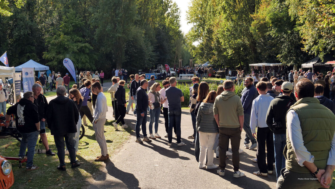 Foule de visiteurs sur l'allée du parc, entre les stands et la nature