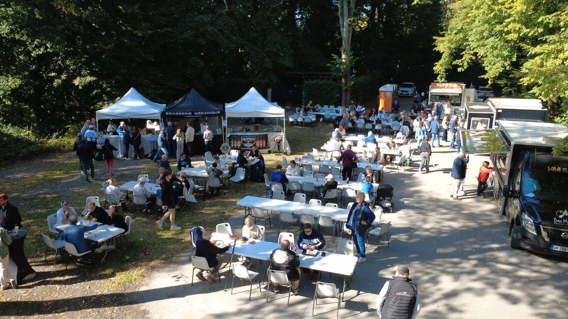 Vue d'ensemble de l'espace restauration avec tables, food trucks et convives